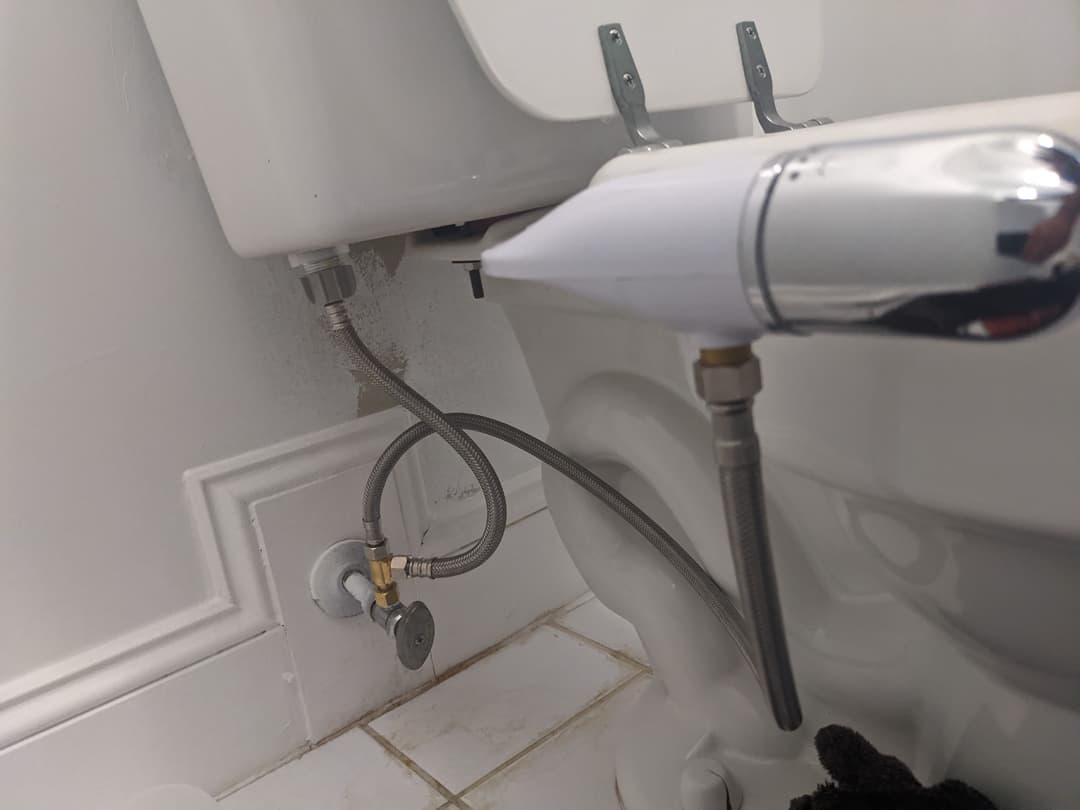 Toilet tank plumbing and water supply line details in a bathroom setting.