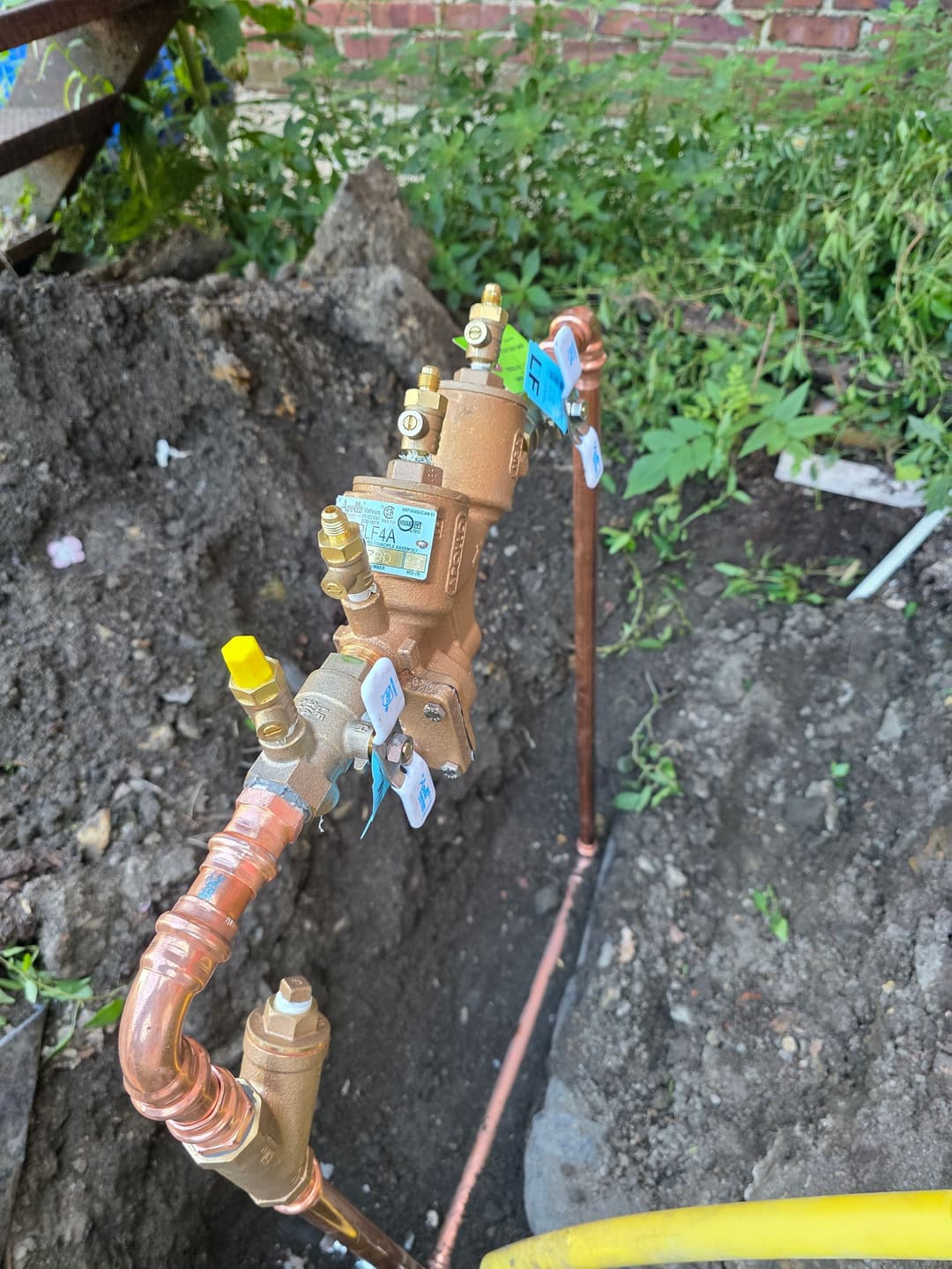 Water service valve and meter installation in a residential yard with grass and dirt.