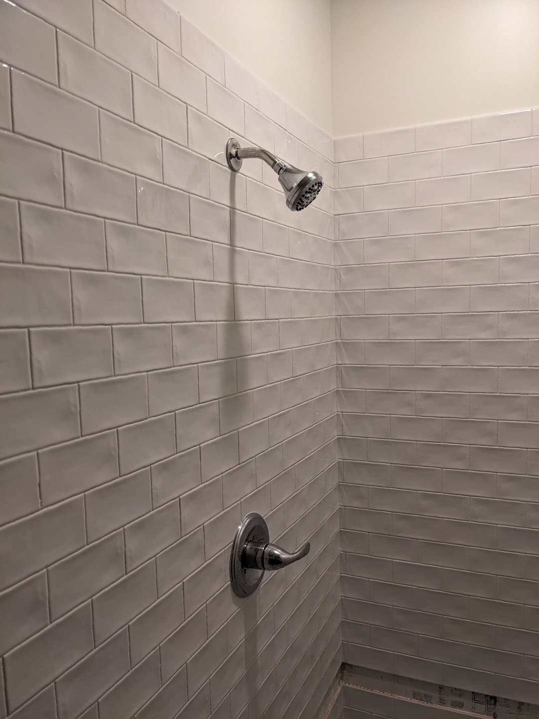 Modern shower with chrome fixtures and white tiled walls in a clean bathroom setting.