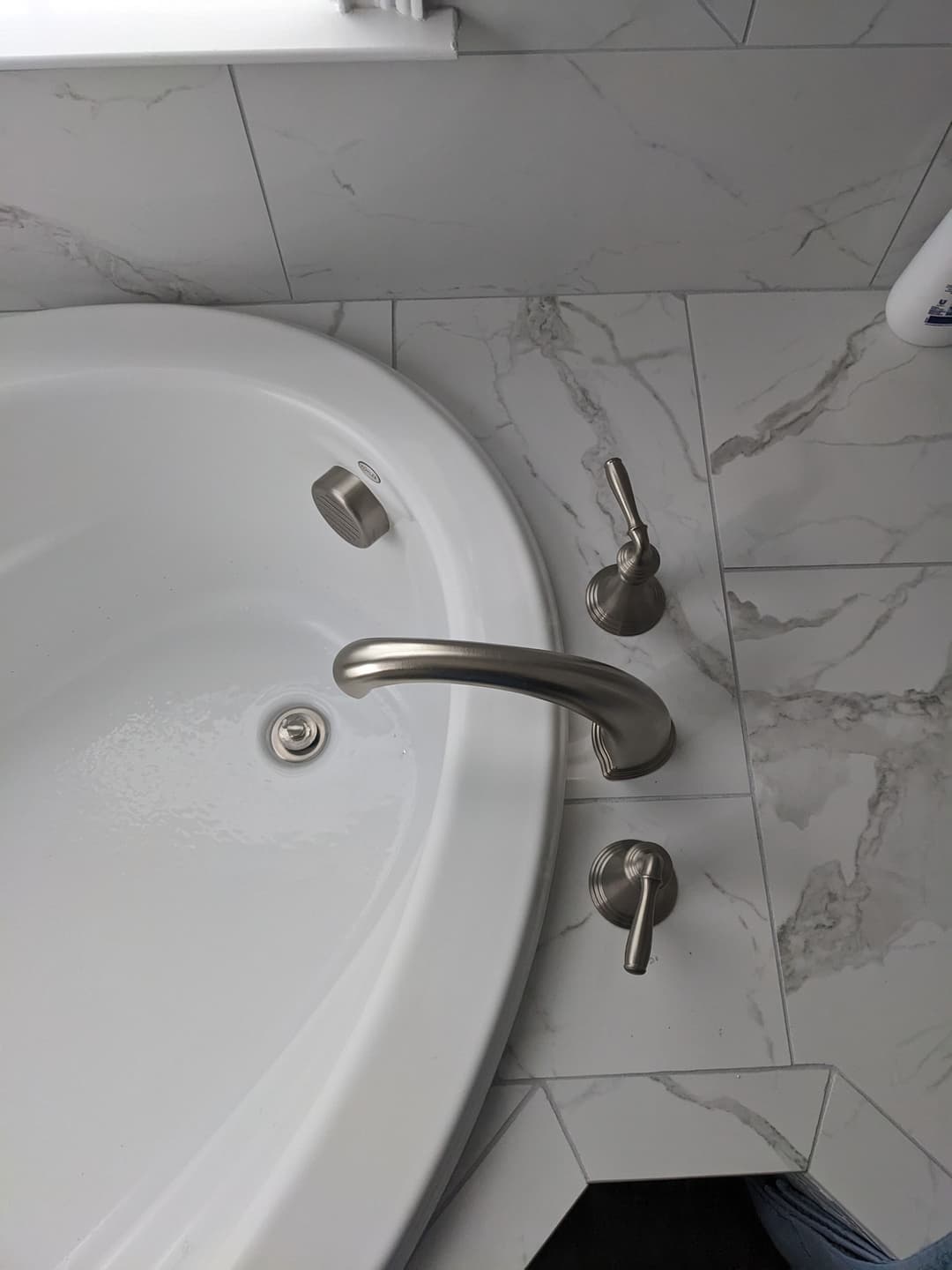 Luxury bathtub with modern faucet and controls, set on marble tiles. Clean and elegant design.