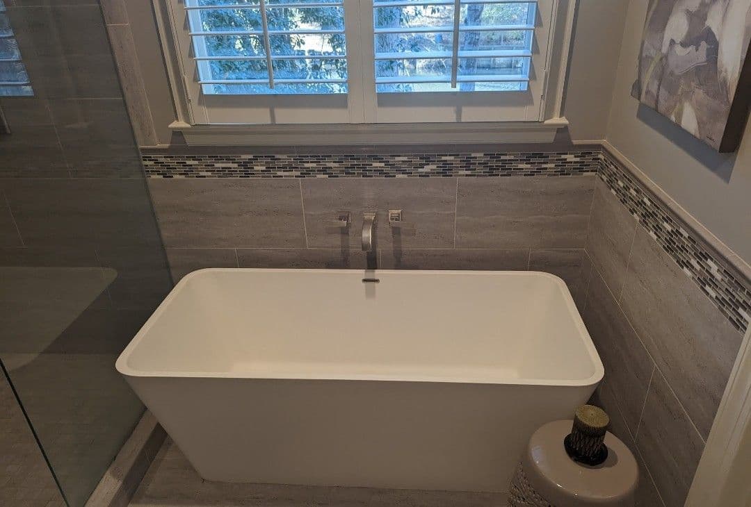Modern freestanding bathtub in elegant bathroom with tiled walls and natural light.