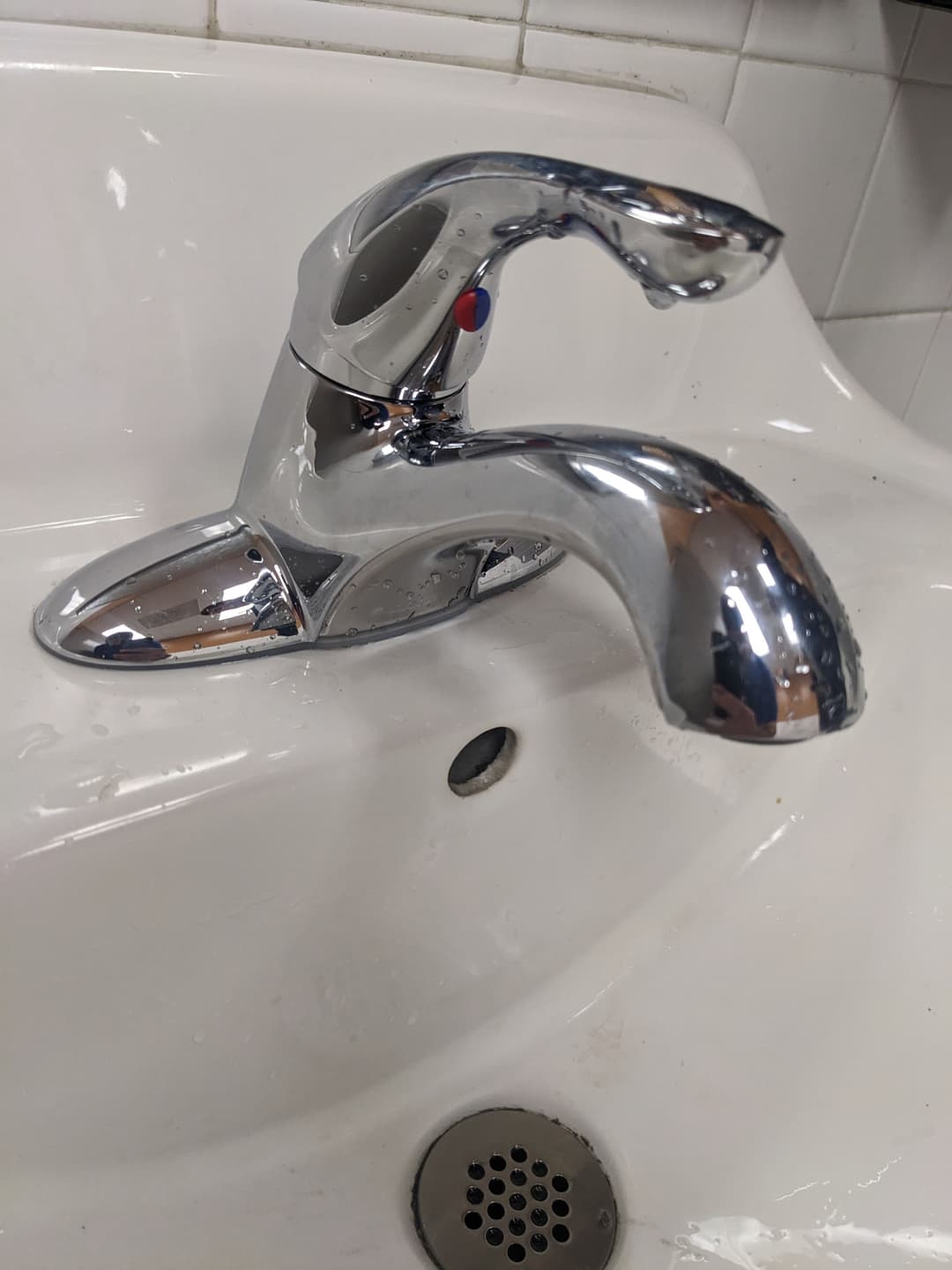 Chrome bathroom faucet with single lever on a white sink.