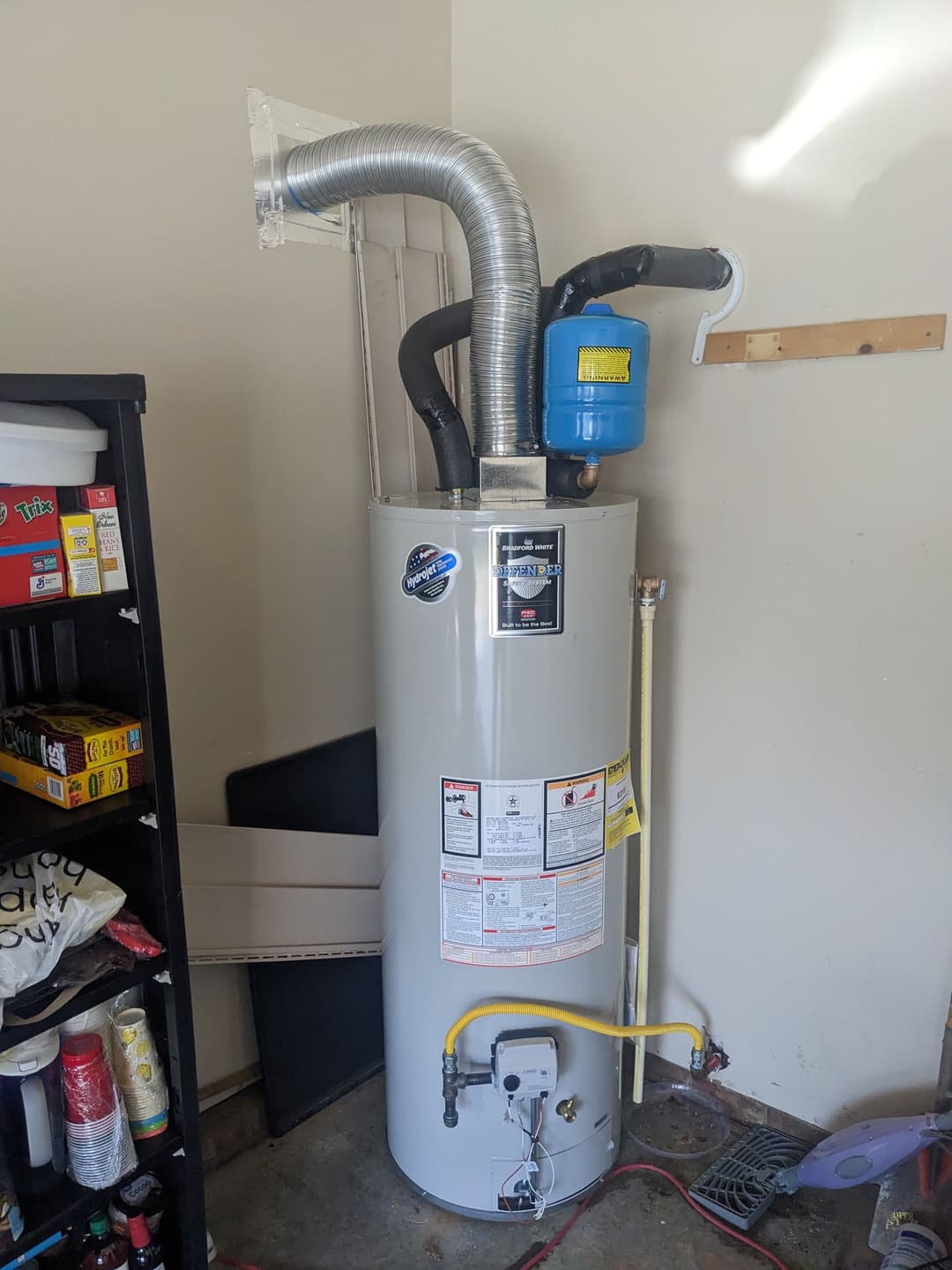 Water heater installed in a garage with venting and safety features visible.