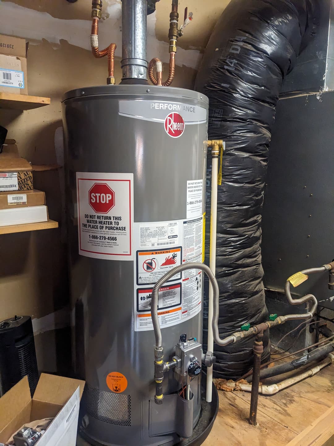 Rheem Performance water heater installed in utility room with pipes and safety notices.